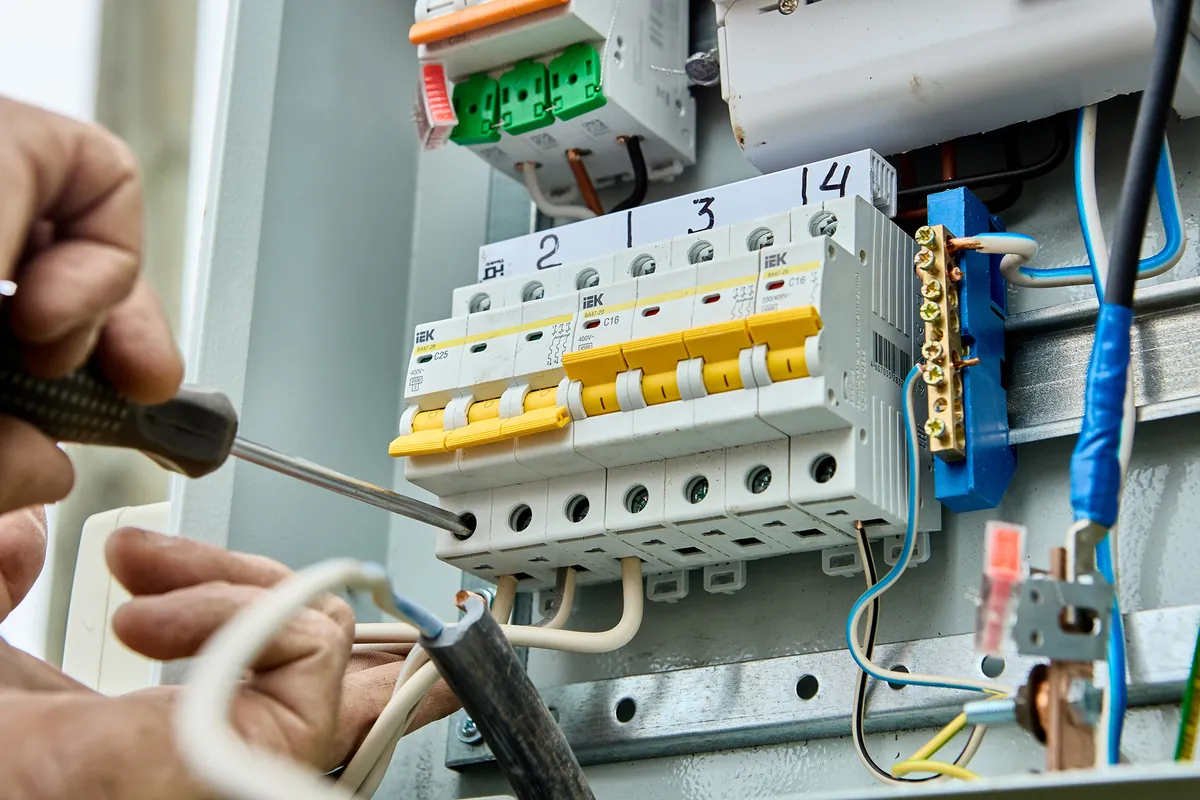 Electrician wiring circuit breakers in a consumer unit, typical work for electricians in Birmingham