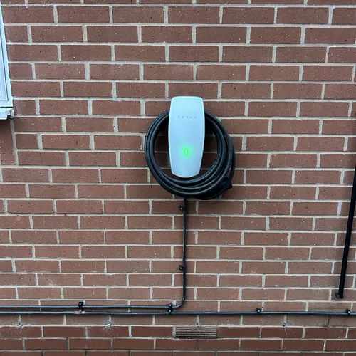 Compact tethered EV charger on a brick wall, a neat choice for a Harborne electrician to fit