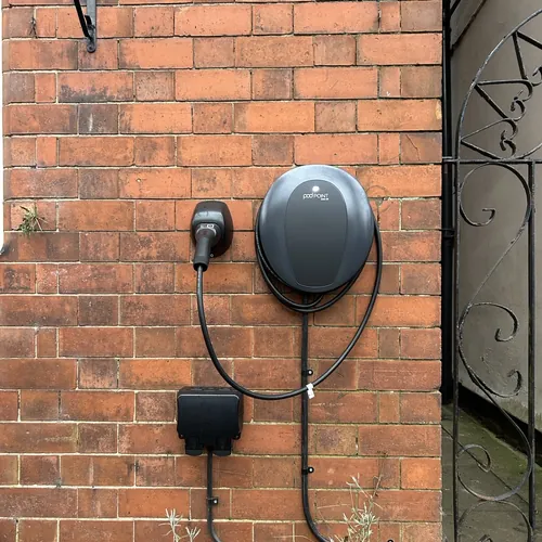 Round smart EV charger beside a garden gate, a discreet option for a Bournville electrician to fit
