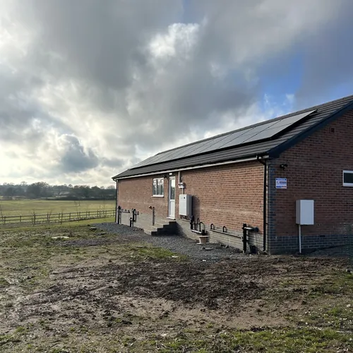 Solar panels on a rural bungalow with the electrics on the side wall