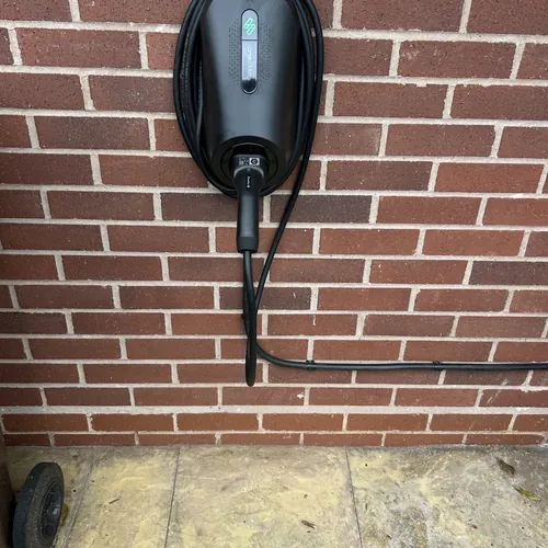 Tethered EV charger on a brick wall, the type of driveway charger our electrician in Hall Green fits on 1930s semis