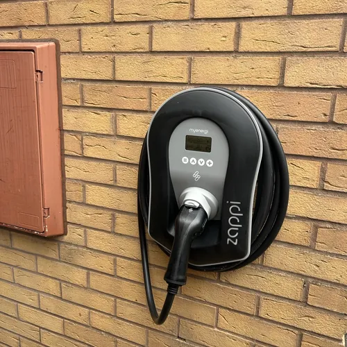 myenergi Zappi charger on a yellow brick wall, solar-ready EV charging by a Shirley electrician