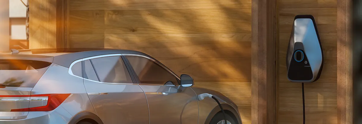 Electric car parked beside a wall-mounted home EV charger in a garage